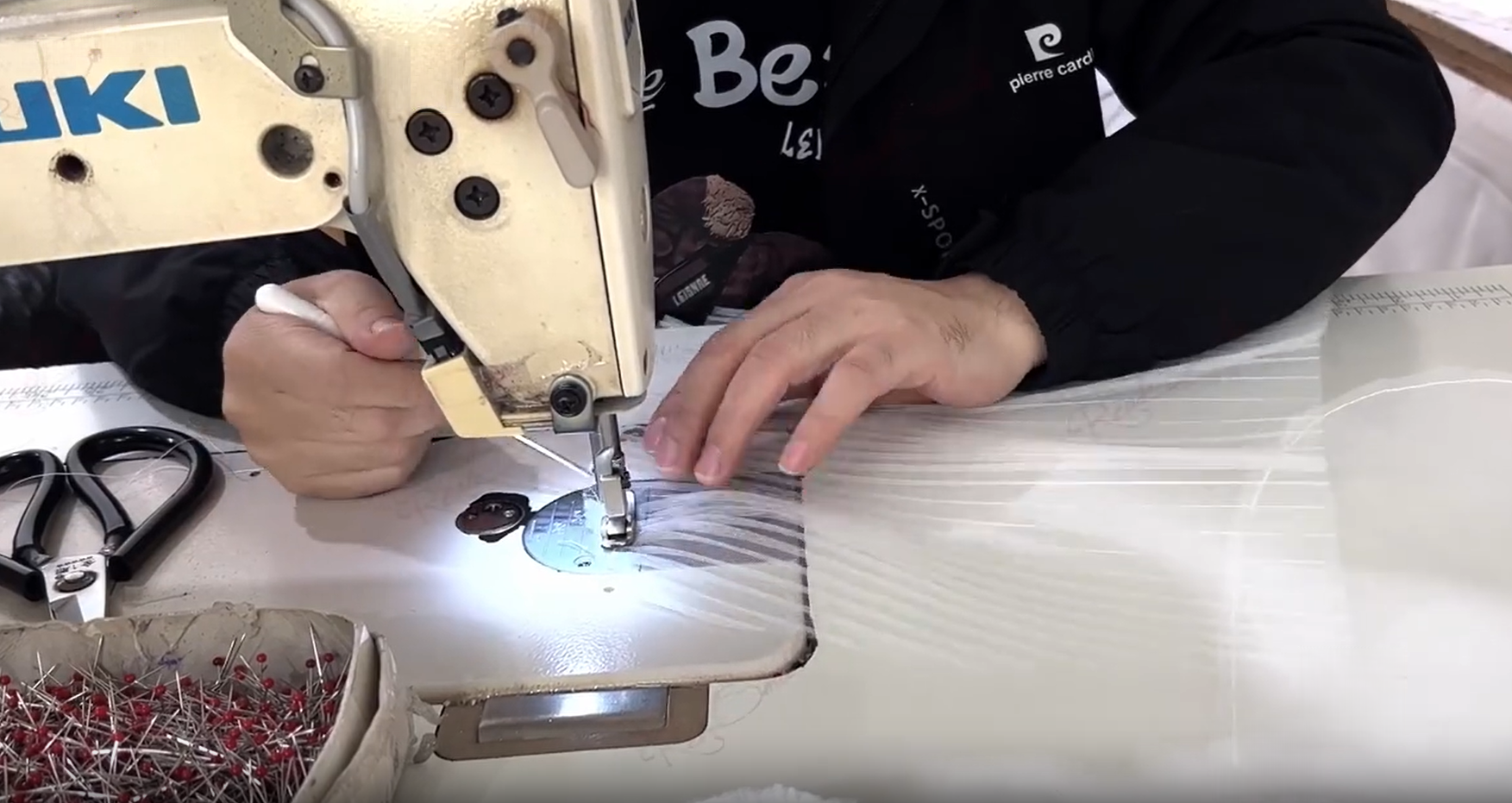 Kemedress tailor using an industrial sewing machine to press and shape pleats for a wedding gown