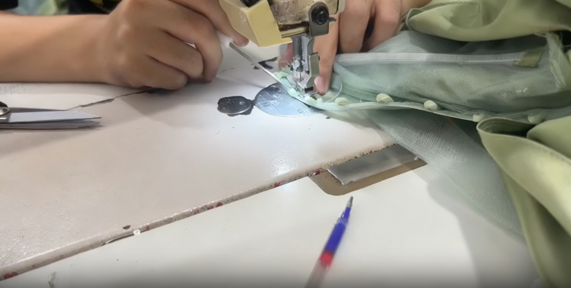 Sewing machine stitching a concealed zipper onto the back of the mint green dress Sewing machine stitching a concealed zipper onto the back of the mint green dress