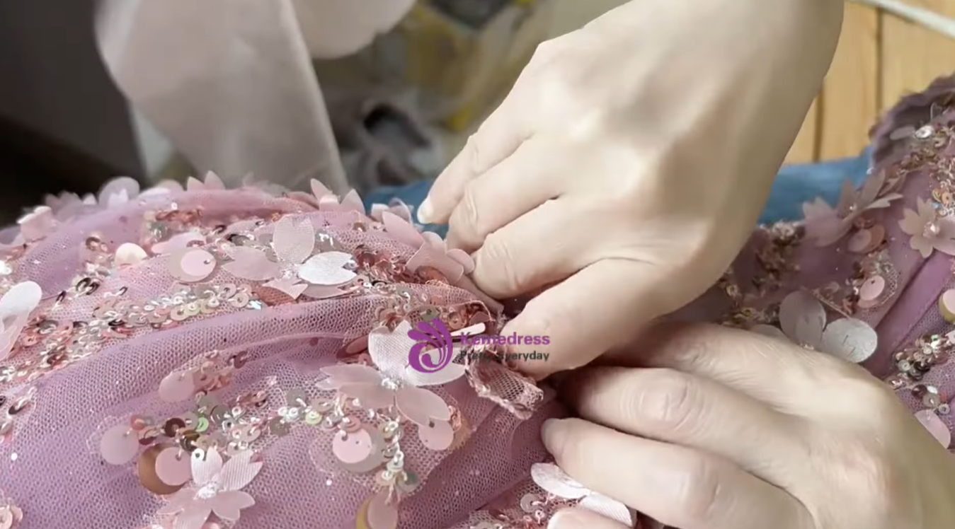 hand sewing floral appliques and sequins onto pink ball gown
