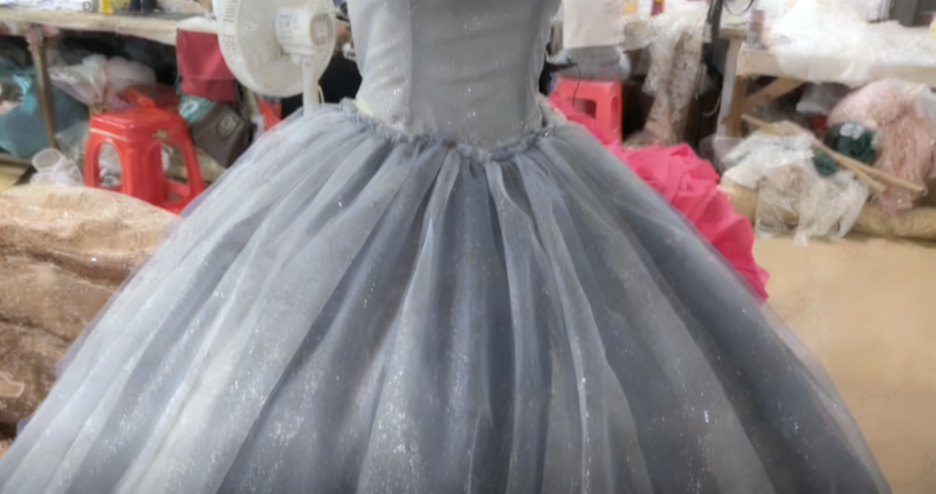Close up of gathered blue glitter tulle at the waistline during the handmade ball gown construction process in a professional dressmaking workshop Close up of gathered blue glitter tulle at the waistline during the handmade ball gown construction process in a professional dressmaking workshop