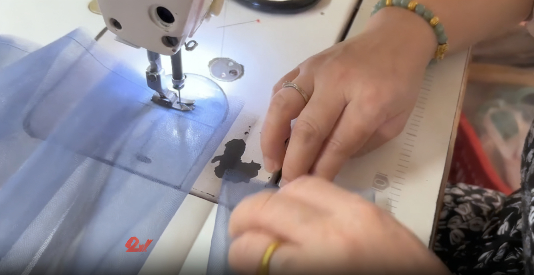 Sewing blue sparkle tulle fabric with an industrial sewing machine during the custom formal gown production process Sewing blue sparkle tulle fabric with an industrial sewing machine during the custom formal gown production process