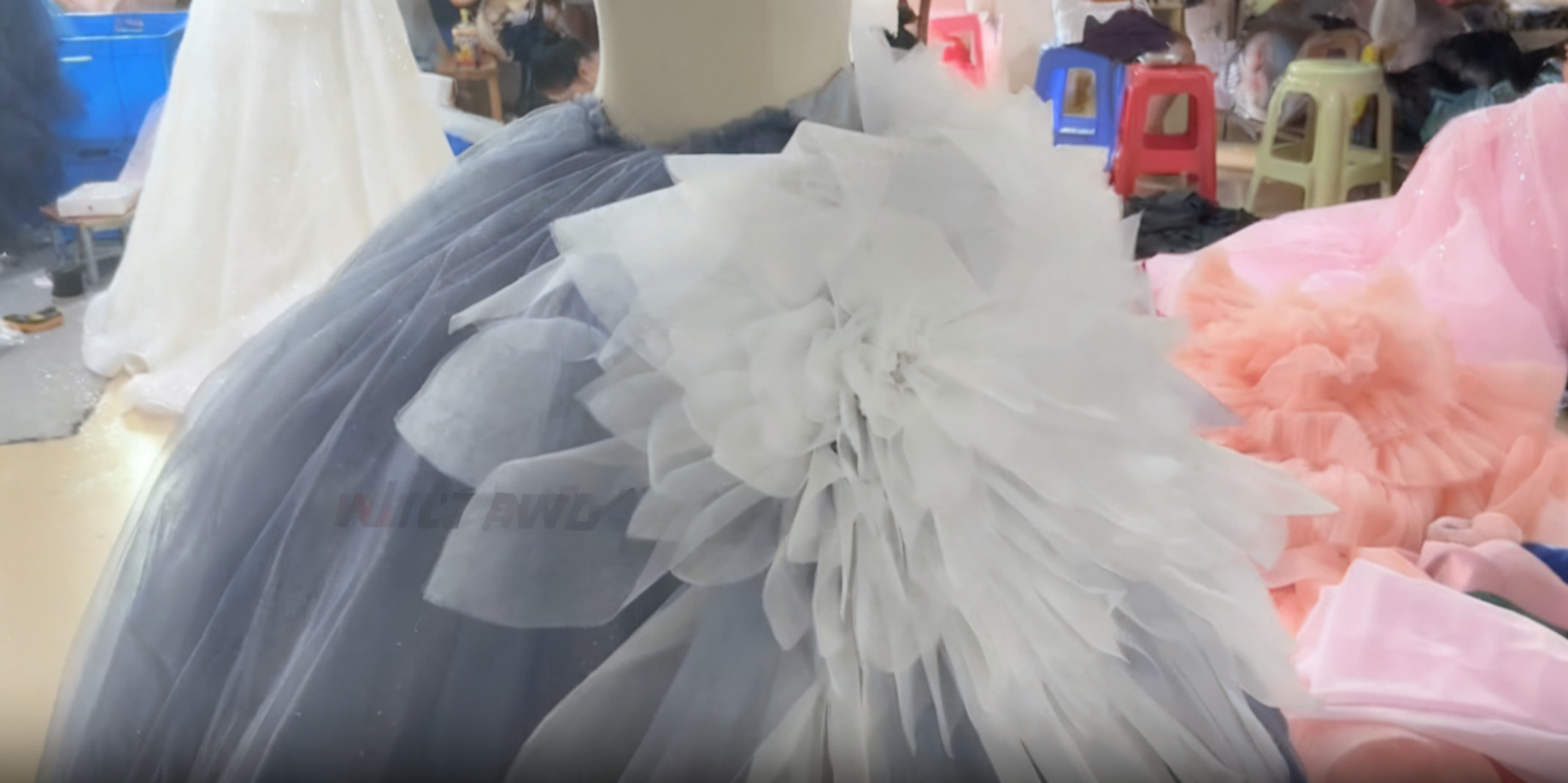 Close up view of cascading white and blue tulle ruffles on a voluminous ombre ball gown during dress construction Close up view of cascading white and blue tulle ruffles on a voluminous ombre ball gown during dress construction