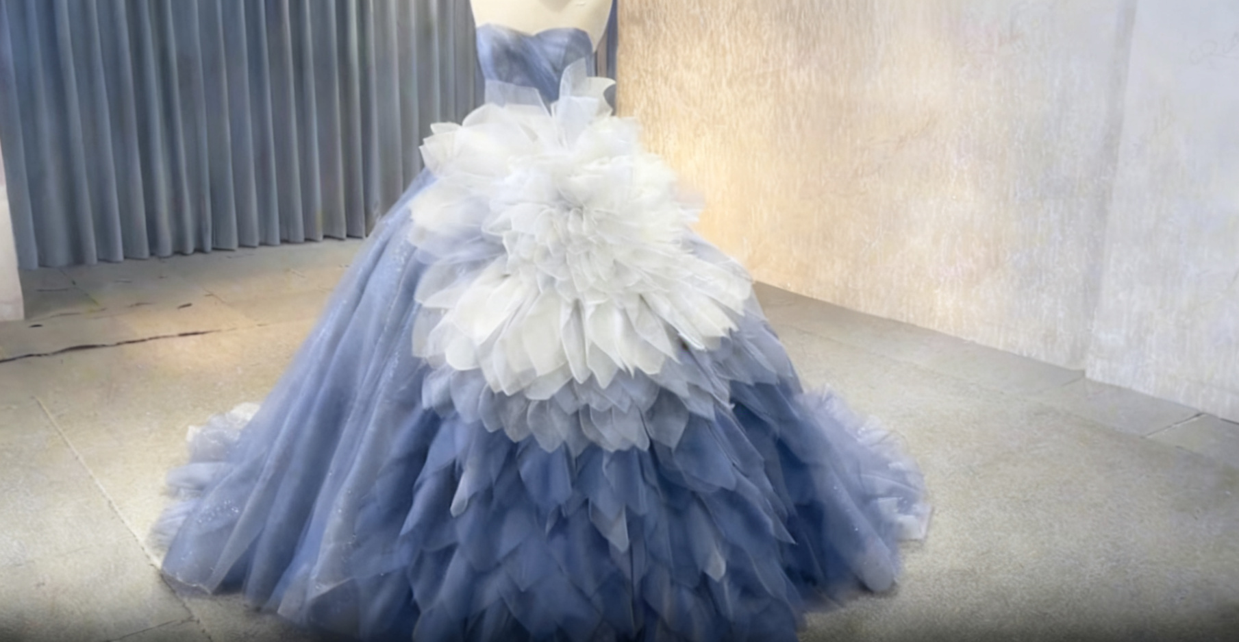 Model wearing a custom blue ombre strapless tulle ball gown with dramatic floral ruffle bodice in a studio setting Model wearing a custom blue ombre strapless tulle ball gown with dramatic floral ruffle bodice in a studio setting