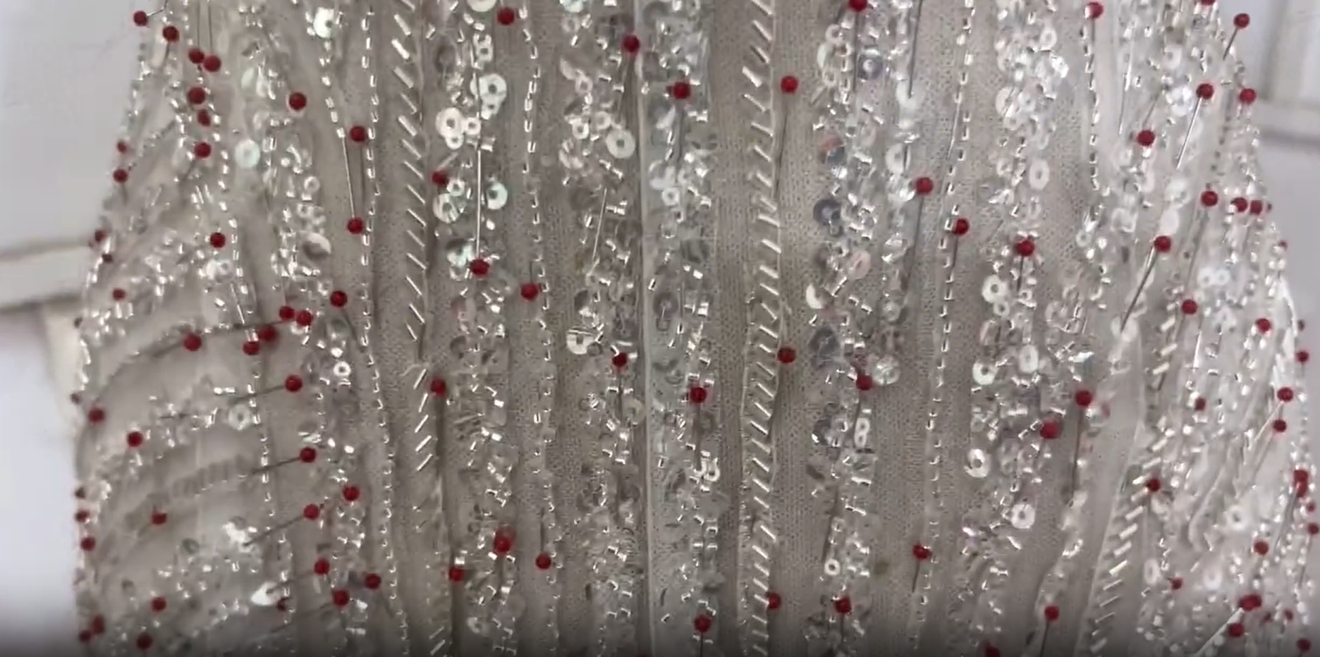 Hand sewing bead trim onto a custom bridal gown neckline Hand sewing bead trim onto a custom bridal gown neckline