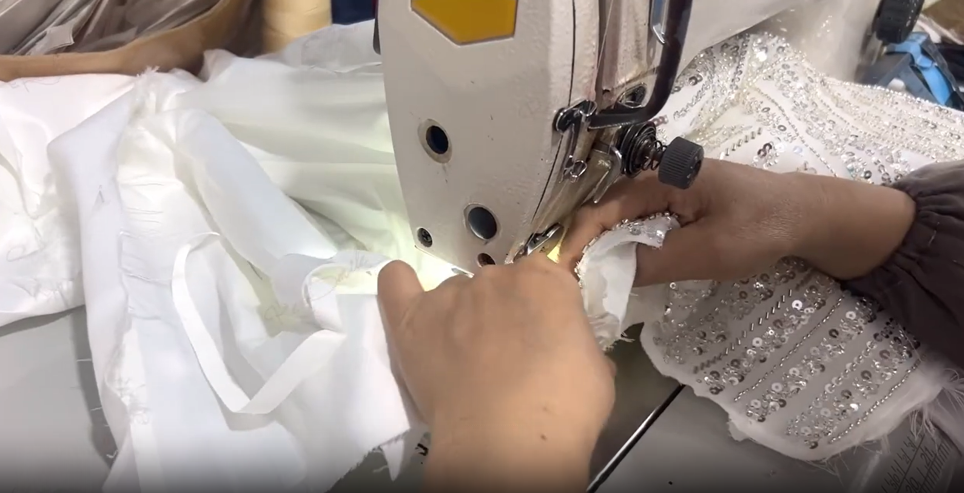 Close-up showing the meticulous hand-pinning process using red-headed pins to secure rows of silver sequins, bugle beads, and lace onto the sheer mesh bodice of the gown. Close-up showing the meticulous hand-pinning process using red-headed pins to secure rows of silver sequins, bugle beads, and lace onto the sheer mesh bodice of the gown.