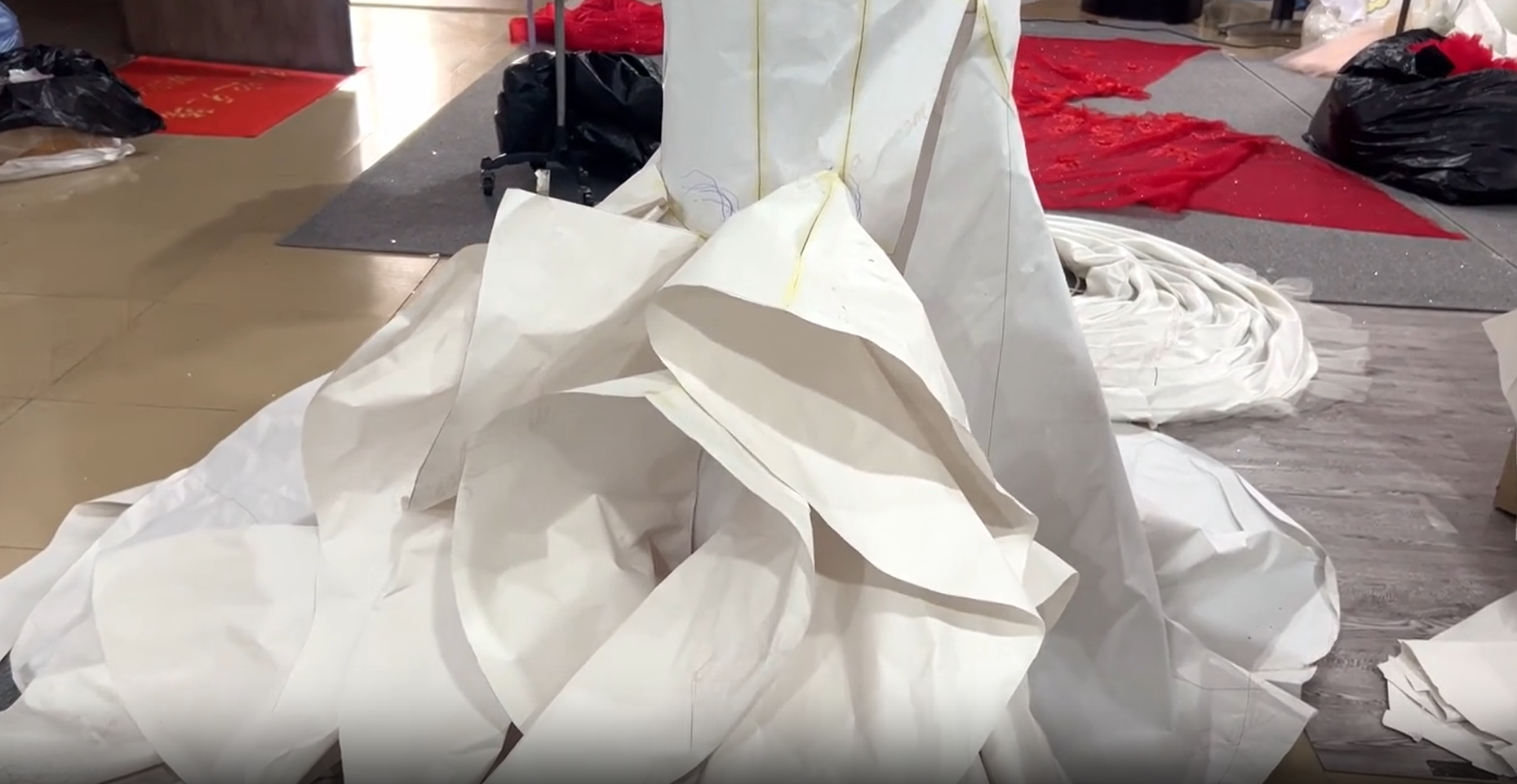 Draping and fitting the white fabric for the wedding dress train. Draping and fitting the white fabric for the wedding dress train.